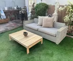 Outdoor rattan sofa with cushions and wooden table